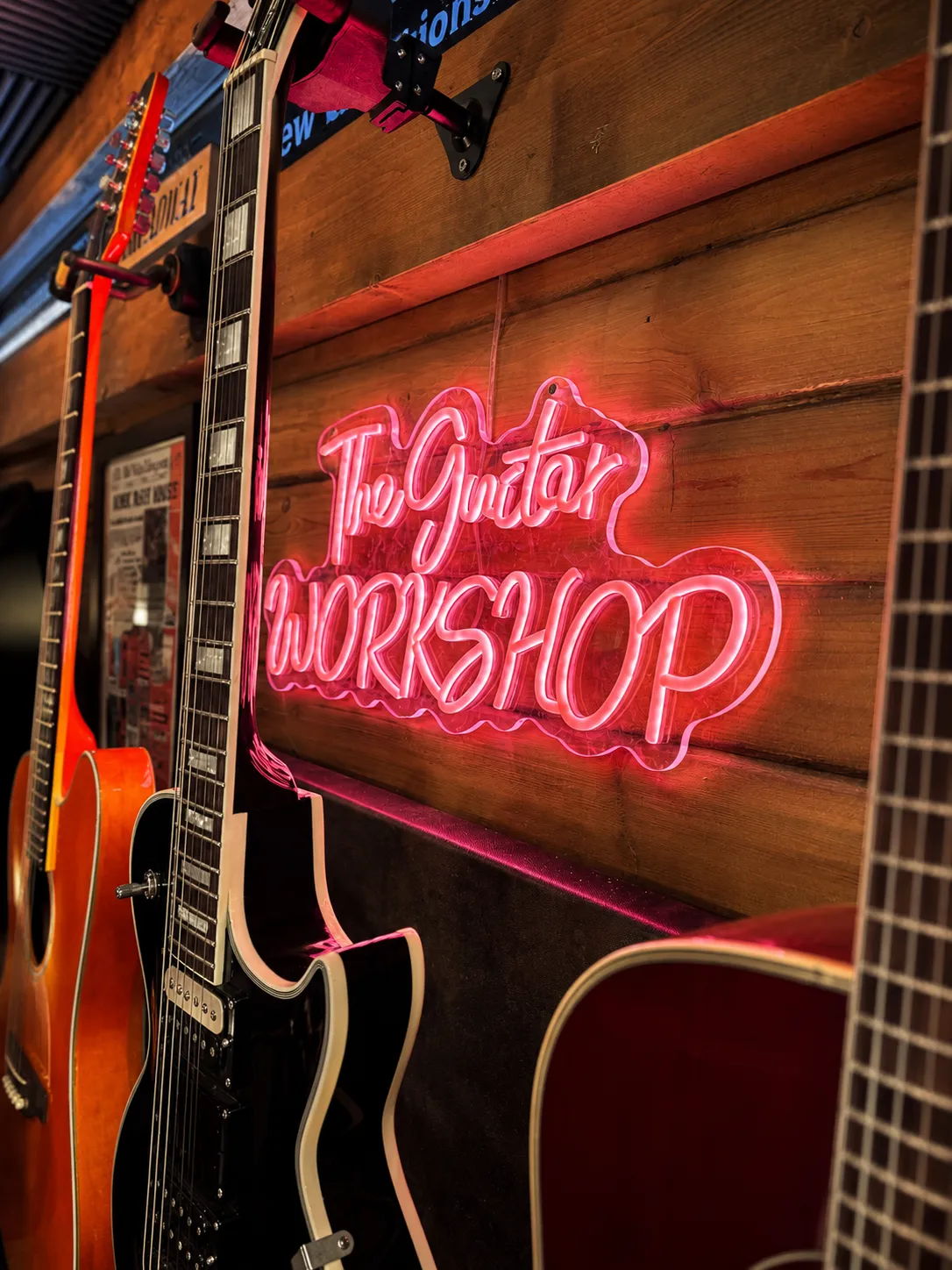 The Guitar Workshop neon sign among guitars at Dave’s studio